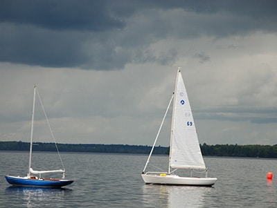 Two sailboats idle under a darkened sky